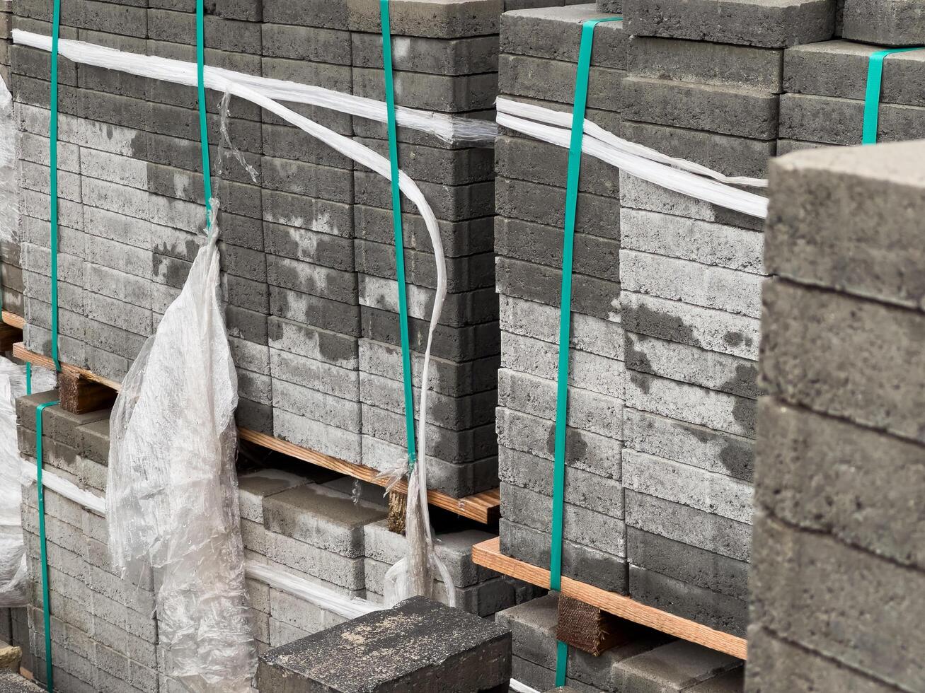 Cobblestones are organized in tall stacks, securely wrapped and prepared for delivery, showcasing their various textures and shades under bright daylight photo