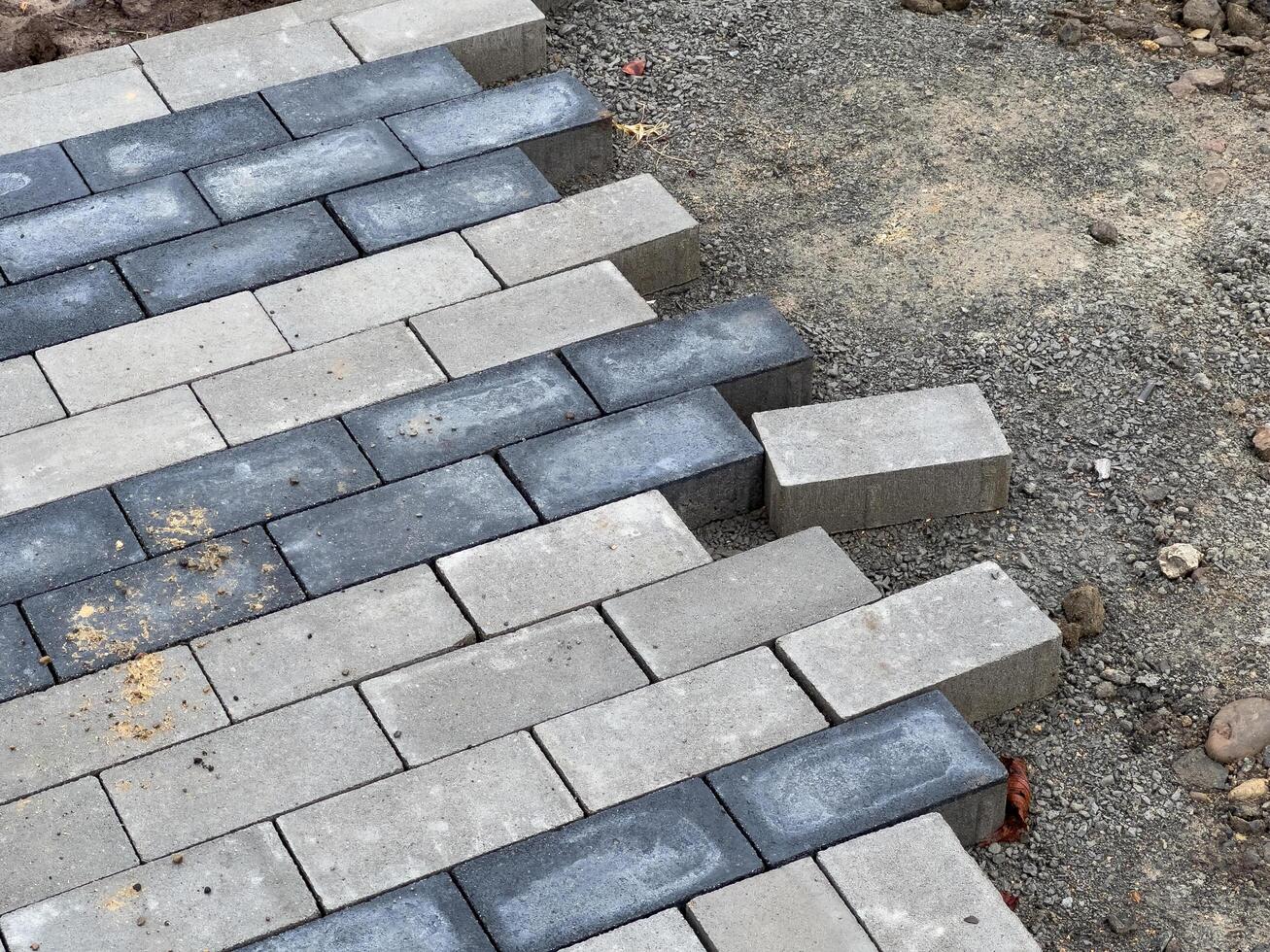 Workers carefully lay the paving stones in a pattern to construct a robust pavement at a construction site, ensuring precise alignment for durability photo