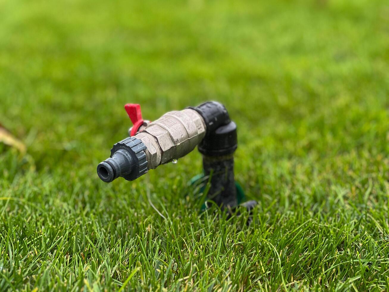 A water faucet stands prominently in a grassy area, showcasing its functionality in a pristine outdoor environment photo