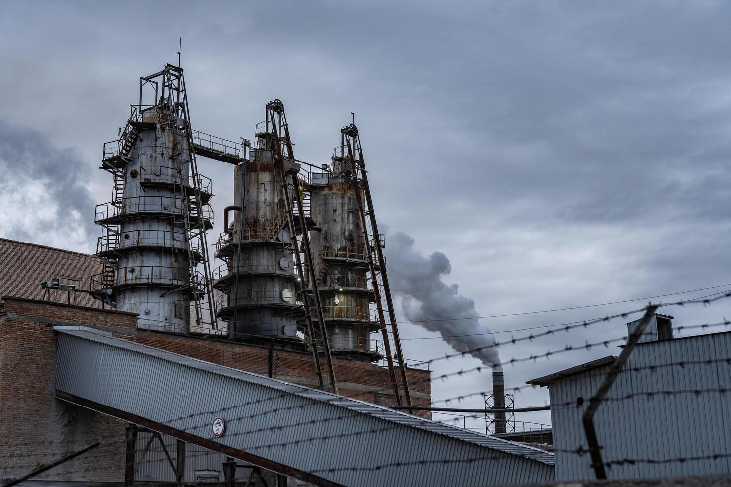 Heavy smoke rises from the tall smokestacks of an industrial facility amid a cloudy sky, reflecting the operations of an urban manufacturing site photo