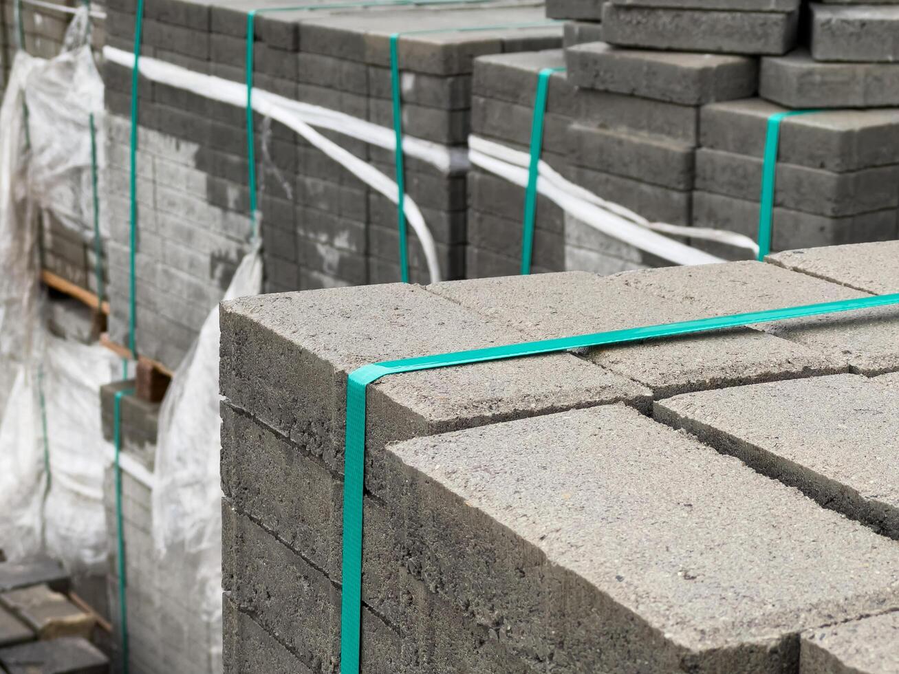 A large stack of cobblestones is neatly bundled and secured with green straps, ready for use in reinforcing sidewalks in an urban environment photo