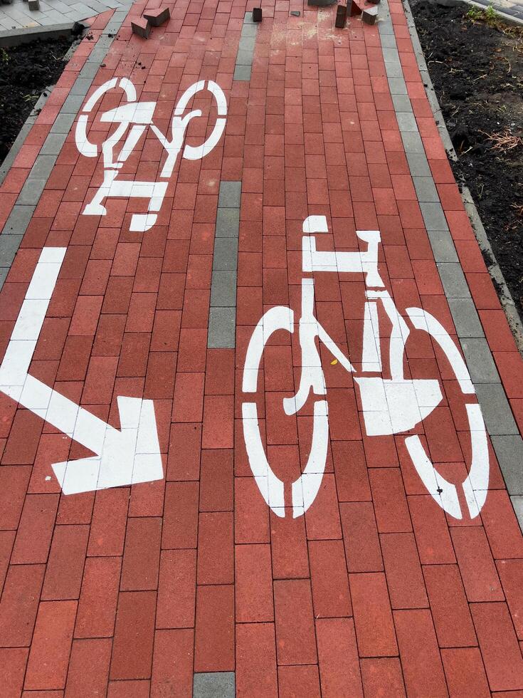 The sidewalk features a bike lane sign with a cyclist graphic and directional arrow, emphasizing the designated path for cyclists in an urban setting photo