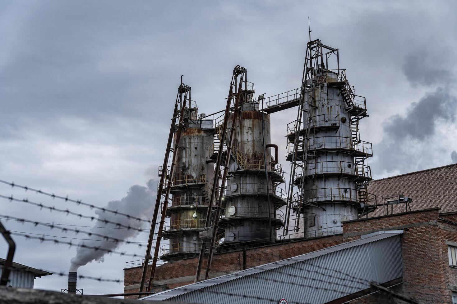 The tall structure features a brick facade and rusted metal supports, standing against a cloudy sky, indicative of an industrial environment in an urban setting photo