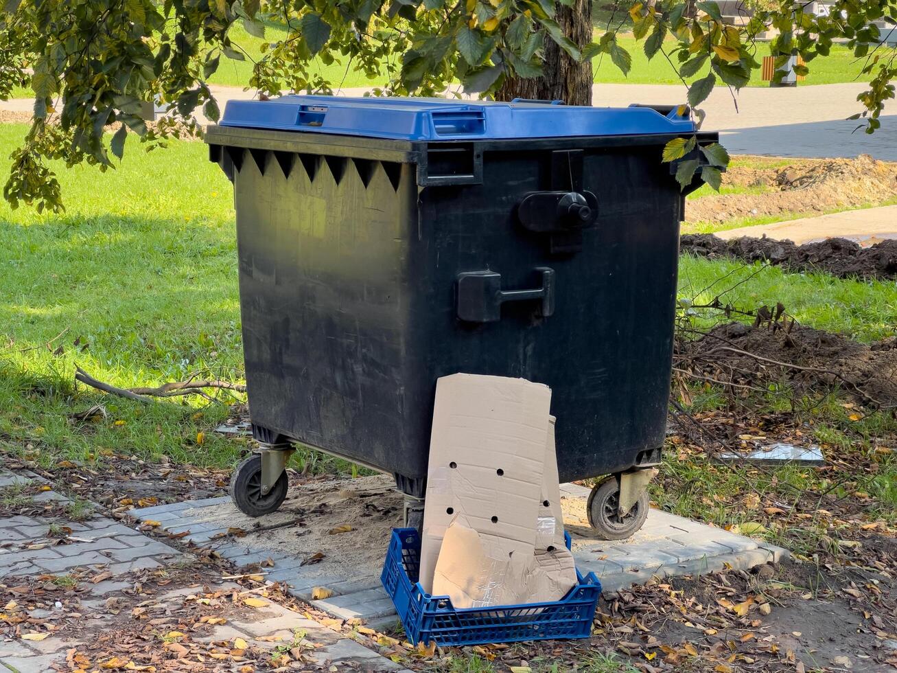 A black trash can with a cardboard box. photo