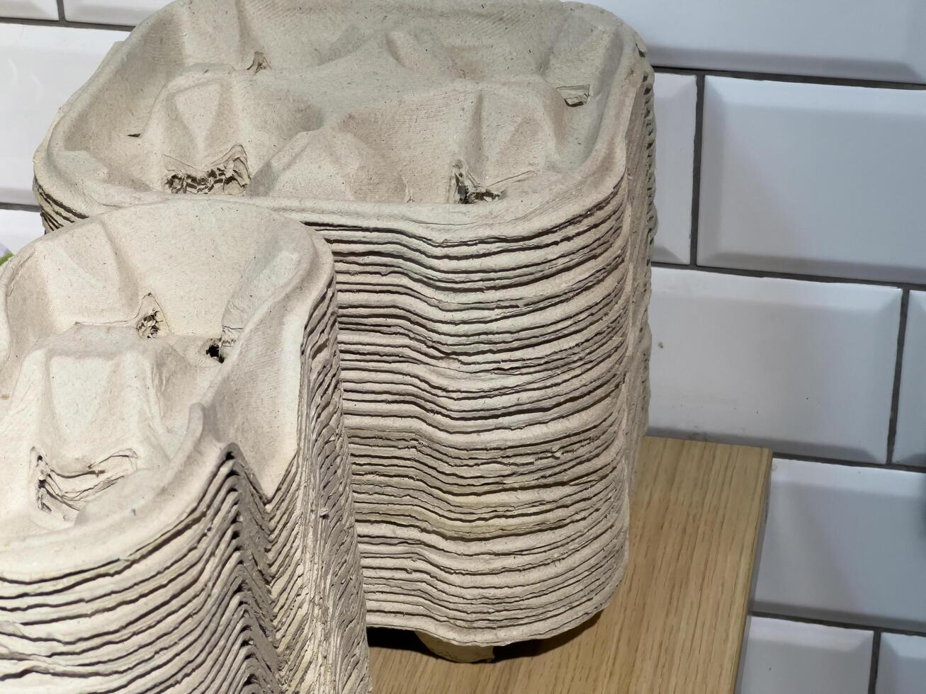 A collection of neatly stacked biodegradable packaging containers sits atop a wooden table, highlighting an eco-conscious approach in a contemporary kitchen space photo