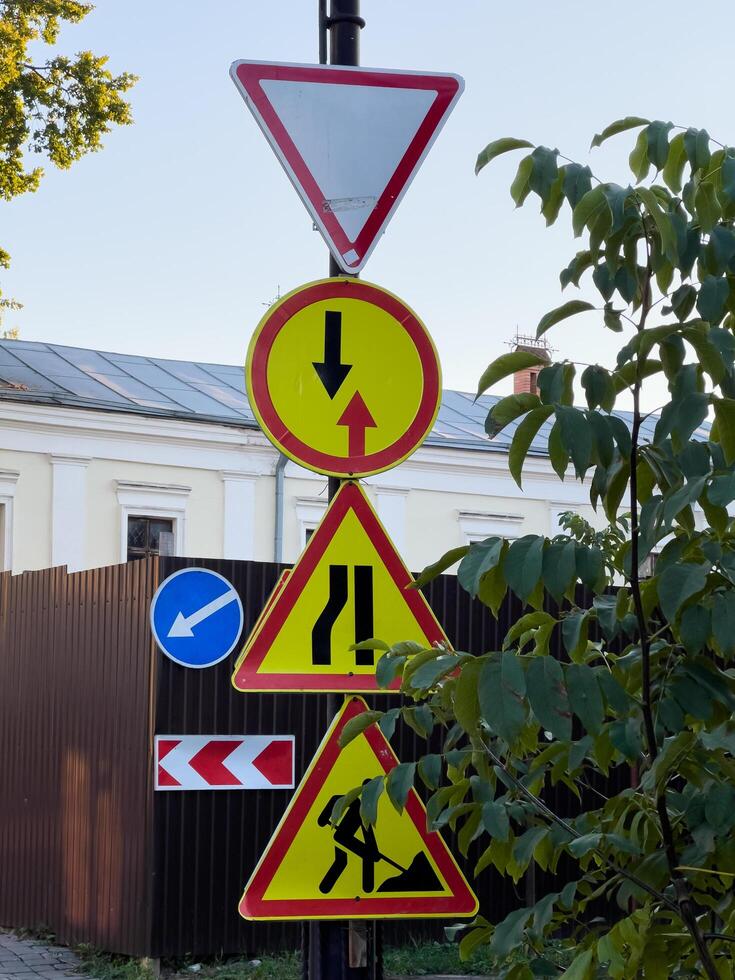 Colorful warning signs indicate various traffic regulations, guiding both pedestrians and vehicles through a busy intersection under clear blue skies photo