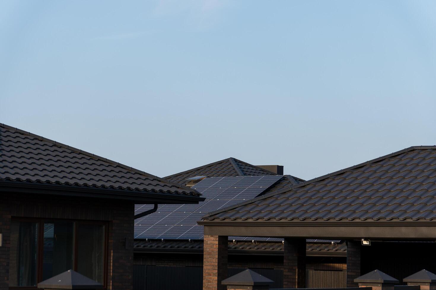 Rooftops adorned with solar panels stretch across a peaceful neighborhood, basking in the gentle warmth of the afternoon sun, highlighting sustainable living photo