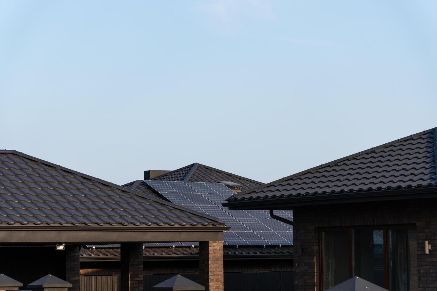 Solar panels are installed on the rooftops of modern homes, showcasing a sustainable energy choice in a quiet suburban area during a sunny day photo