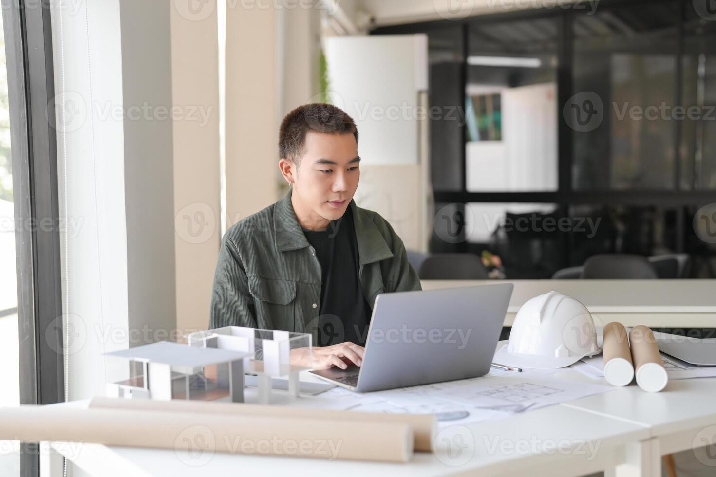 Architecture in a green jacket sitting at a table with a laptop photo