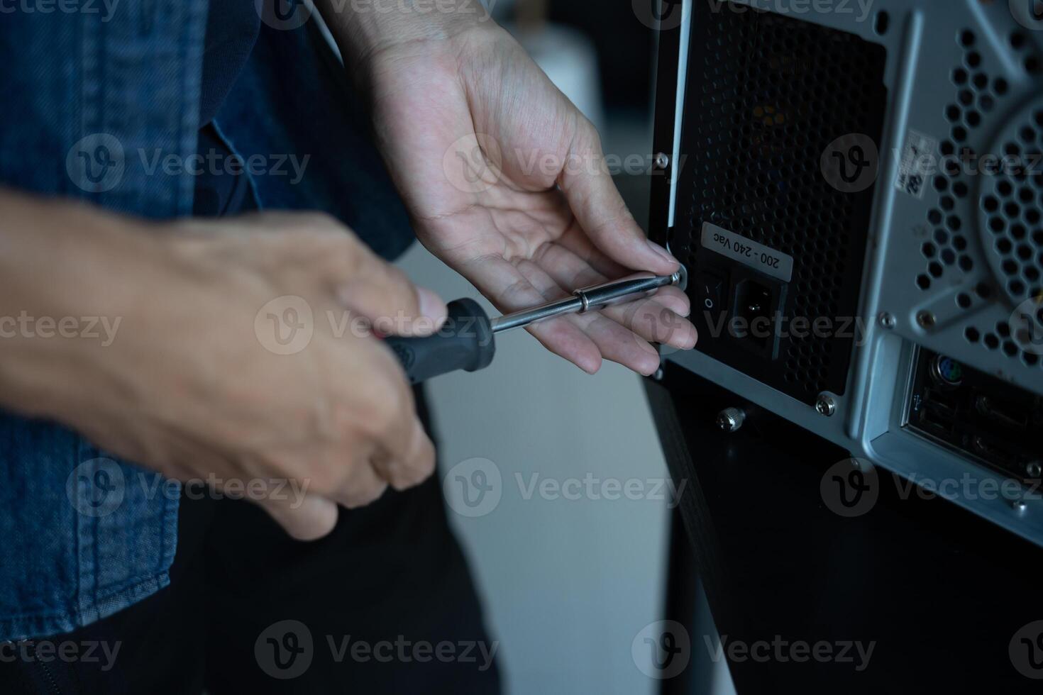 IT Engineer is holding a screwdriver to a computer photo
