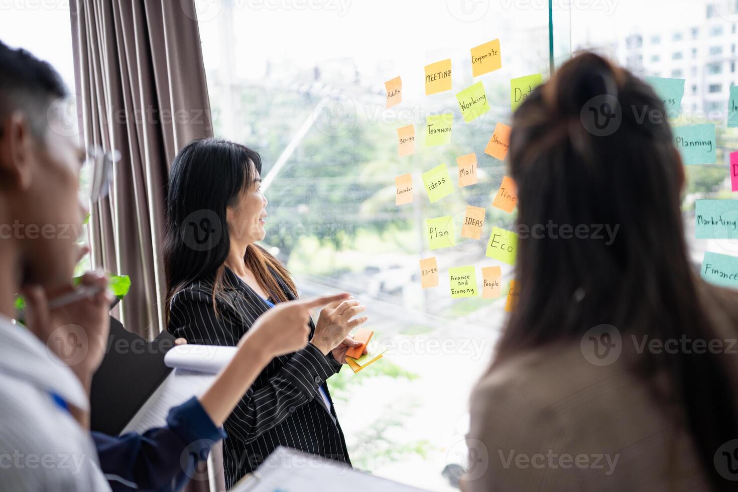 a group of people standing around a window with sticky notes on it. photo