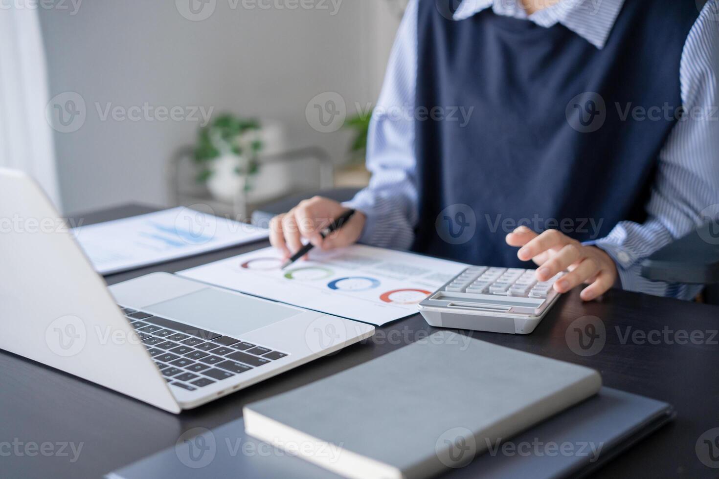 businesswoman doing paper work with pen laptop calculator at office. photo