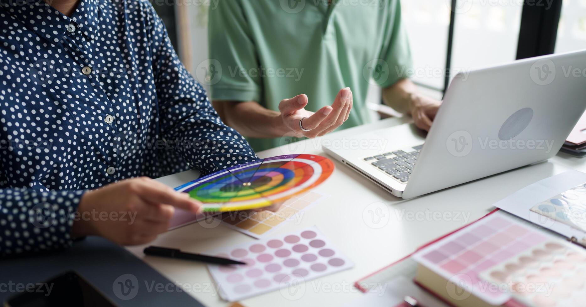 a man and woman are working on a laptop with a color swatch photo