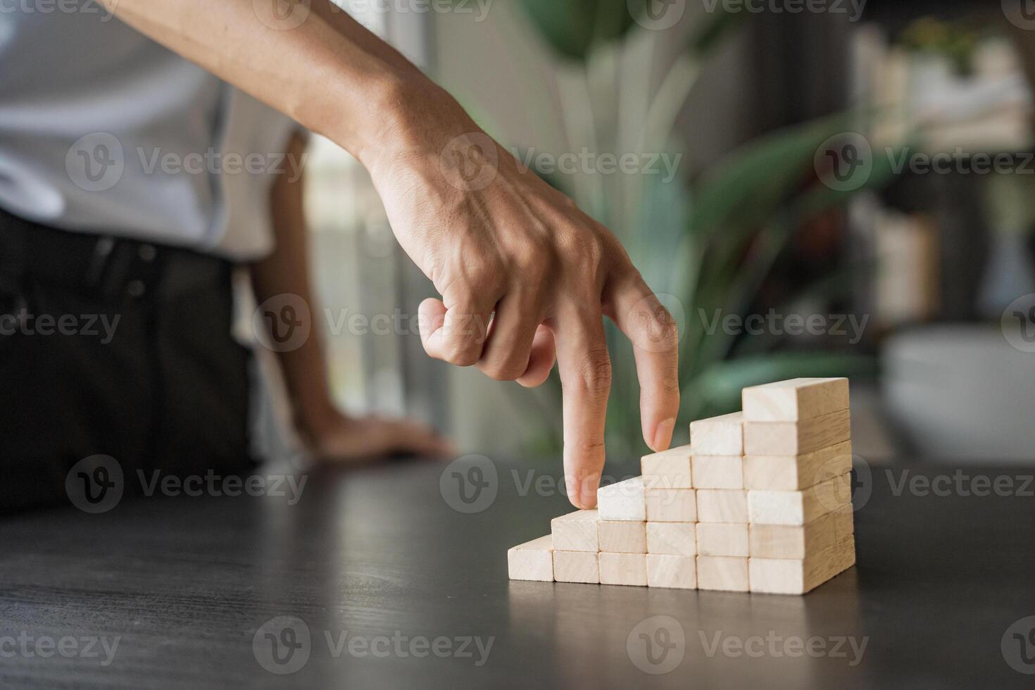 a person is pointing at a wooden block that is made up of cubes, business growth success photo