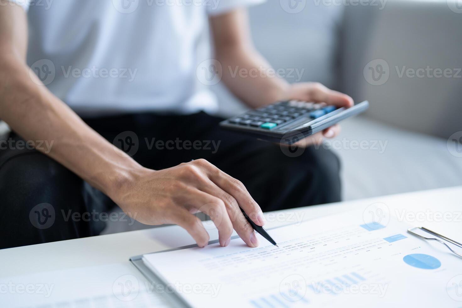man's hand writing on paper with calculator and pen photo
