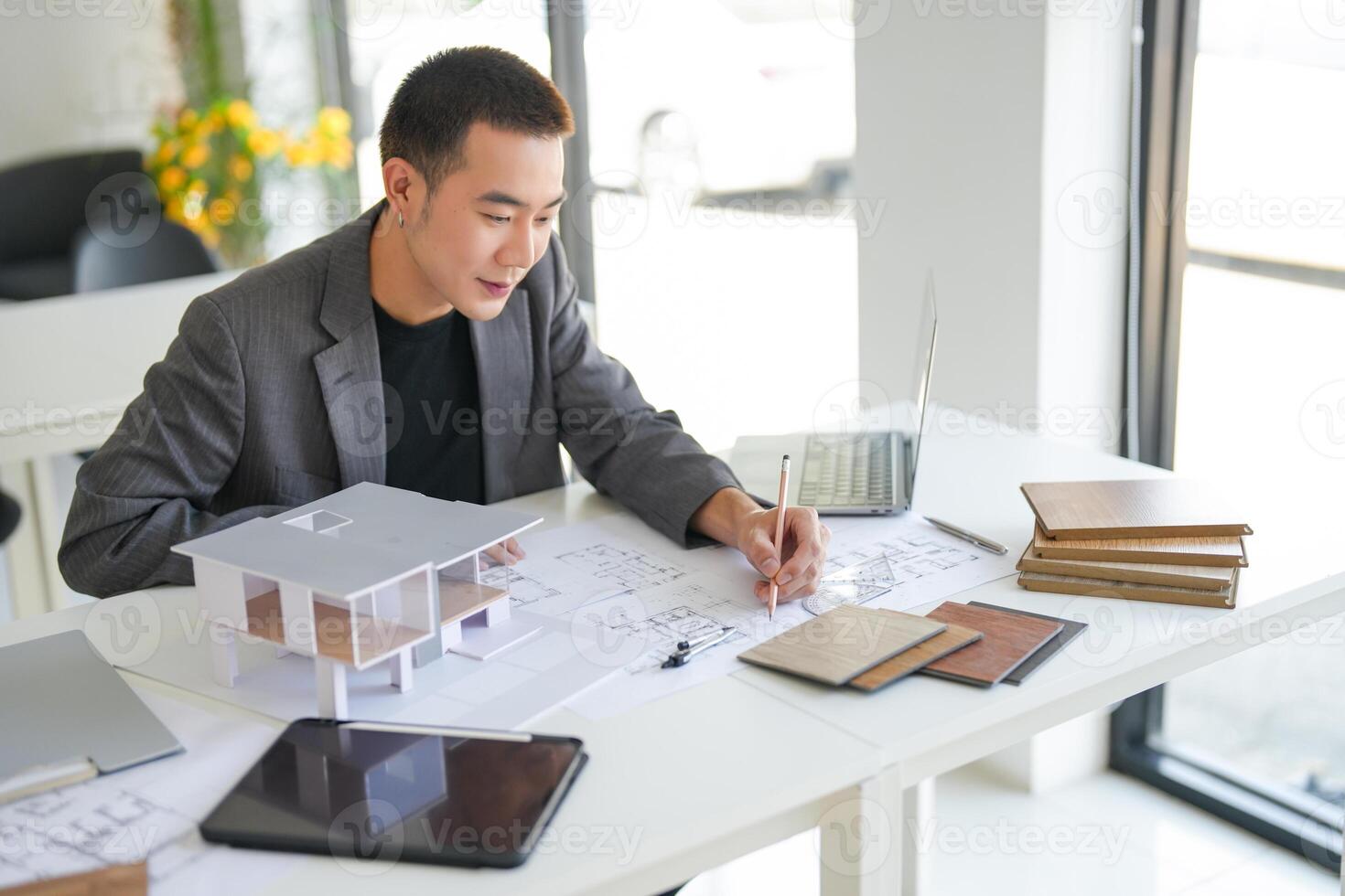 Architecture Man is working on a project with a laptop and a model of a house photo