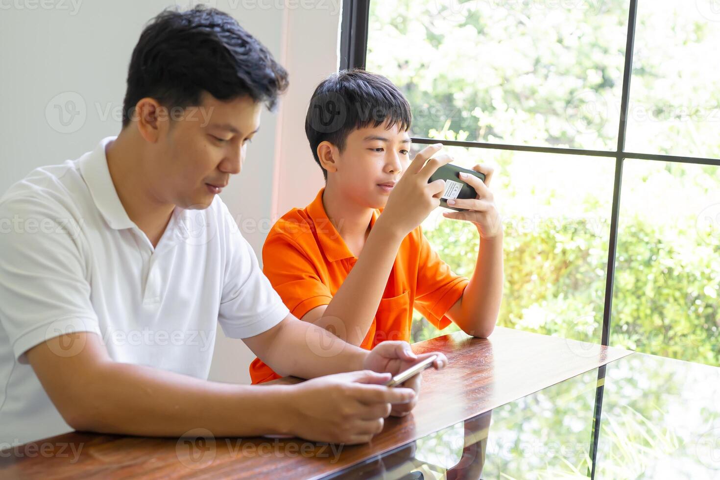 Asian father and son with mobile phone playing games together dad spend time with family photo