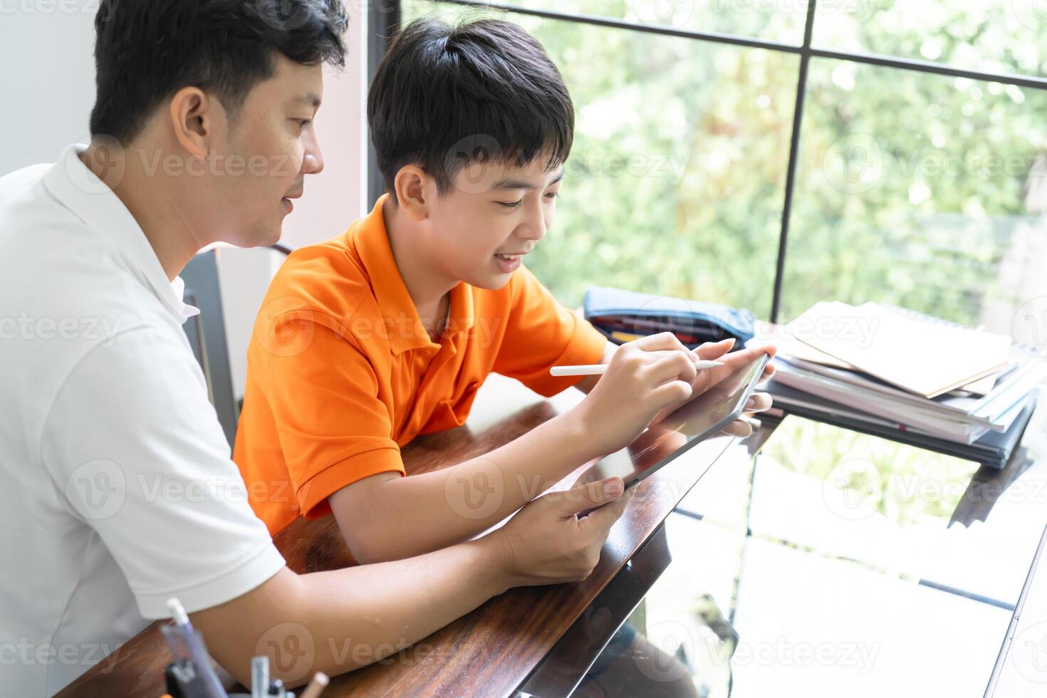 asian father and son working on homework together photo