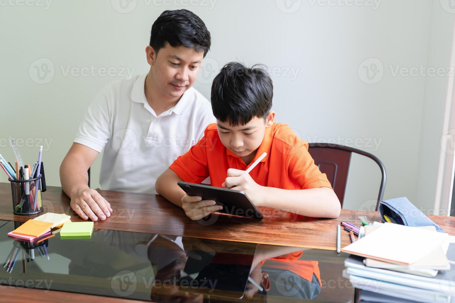 a father and a boy sitting at a table with a tablet photo