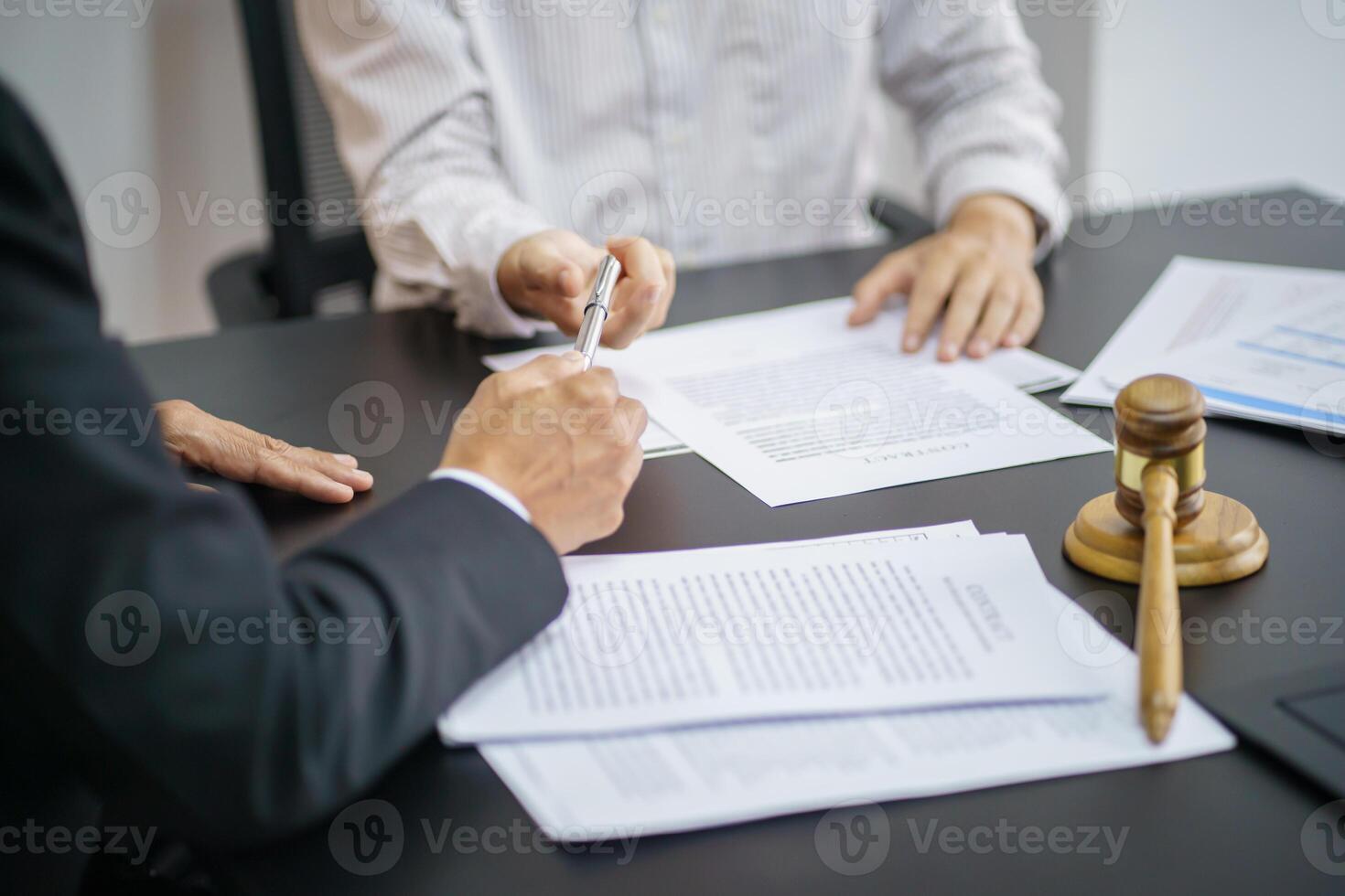 two people sitting at a table with papers and a gavel. photo
