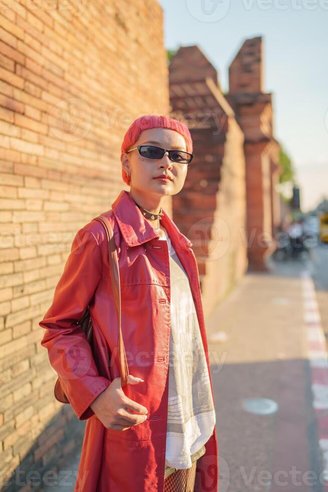 Traveler girl with red hair and sunglasses standing in front of a brick wall photo