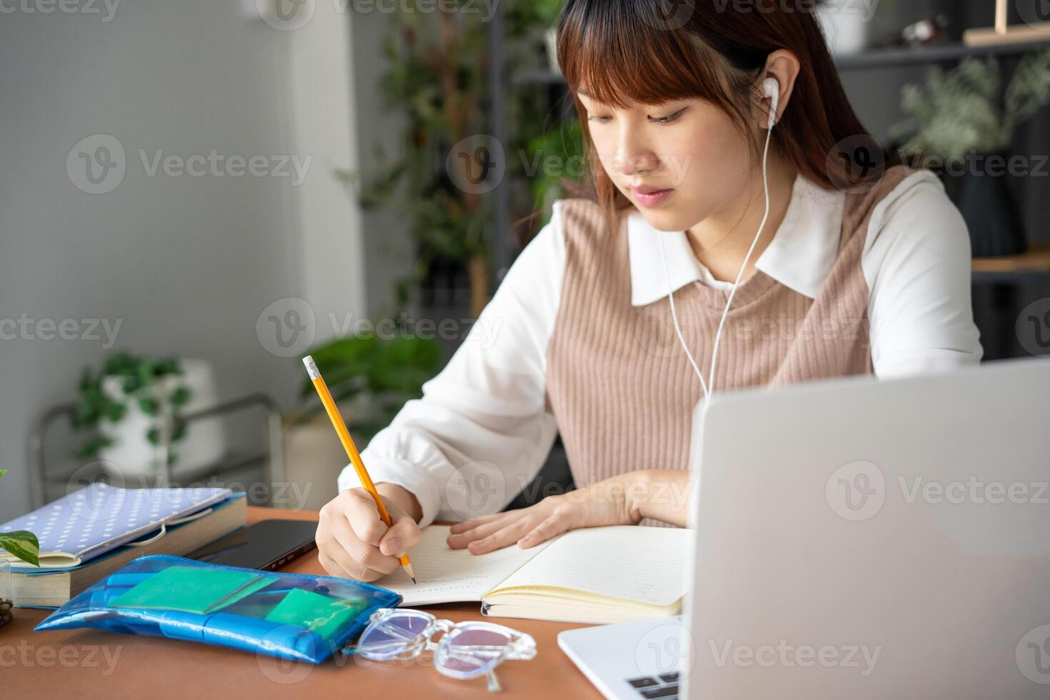 a woman is sitting at a desk with a laptop and a pen. online learning class photo