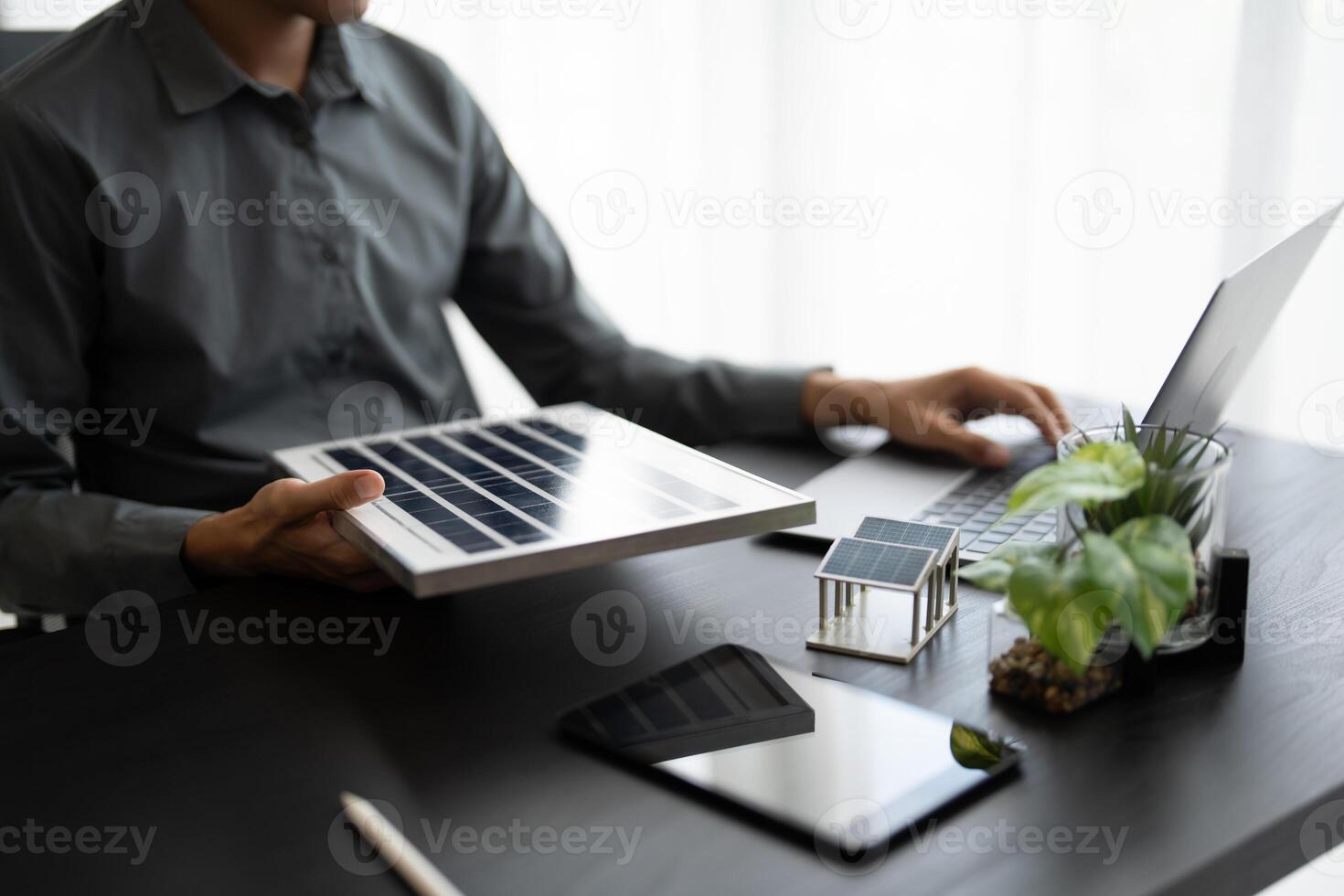 a man is sitting at a desk with a laptop and a tablet Solar panel energy photo
