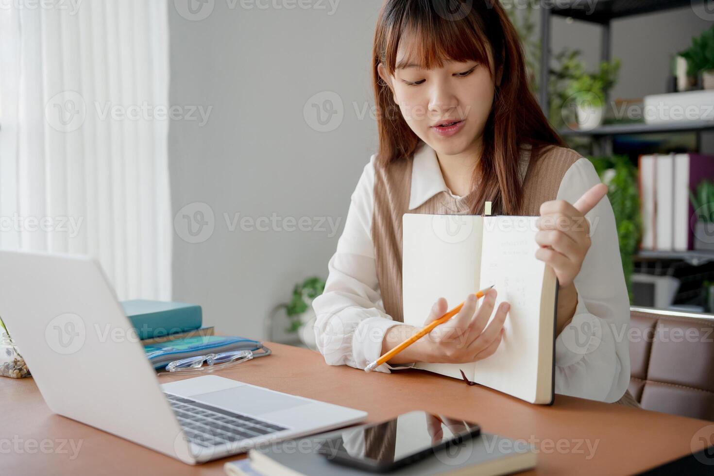 a student woman sitting at a desk with a notebook and pen photo