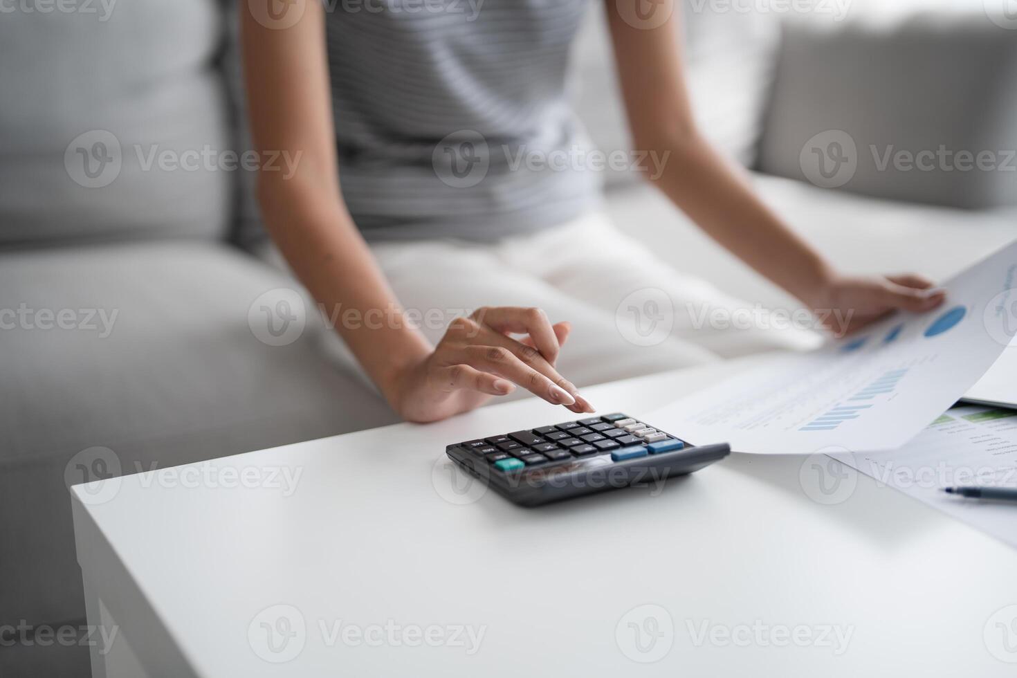 a woman is using a calculator to calculate the cost of a home photo