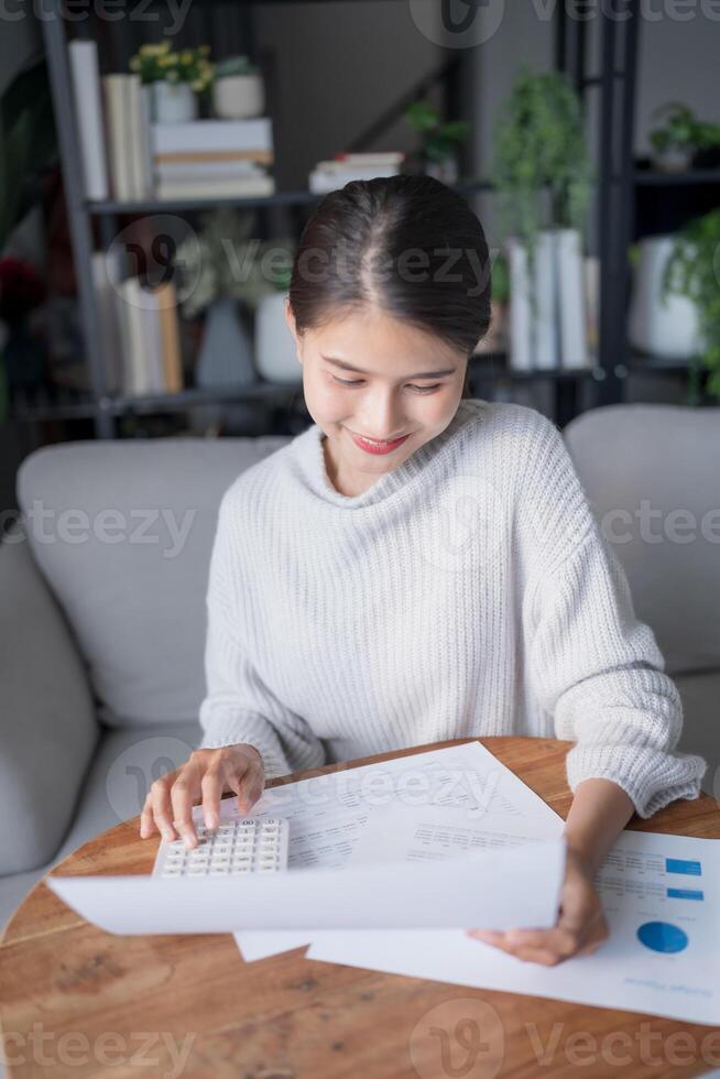 Businesswoman Accountant analyzing investment charts Invoice and pressing calculator buttons over documents. Accounting at home photo