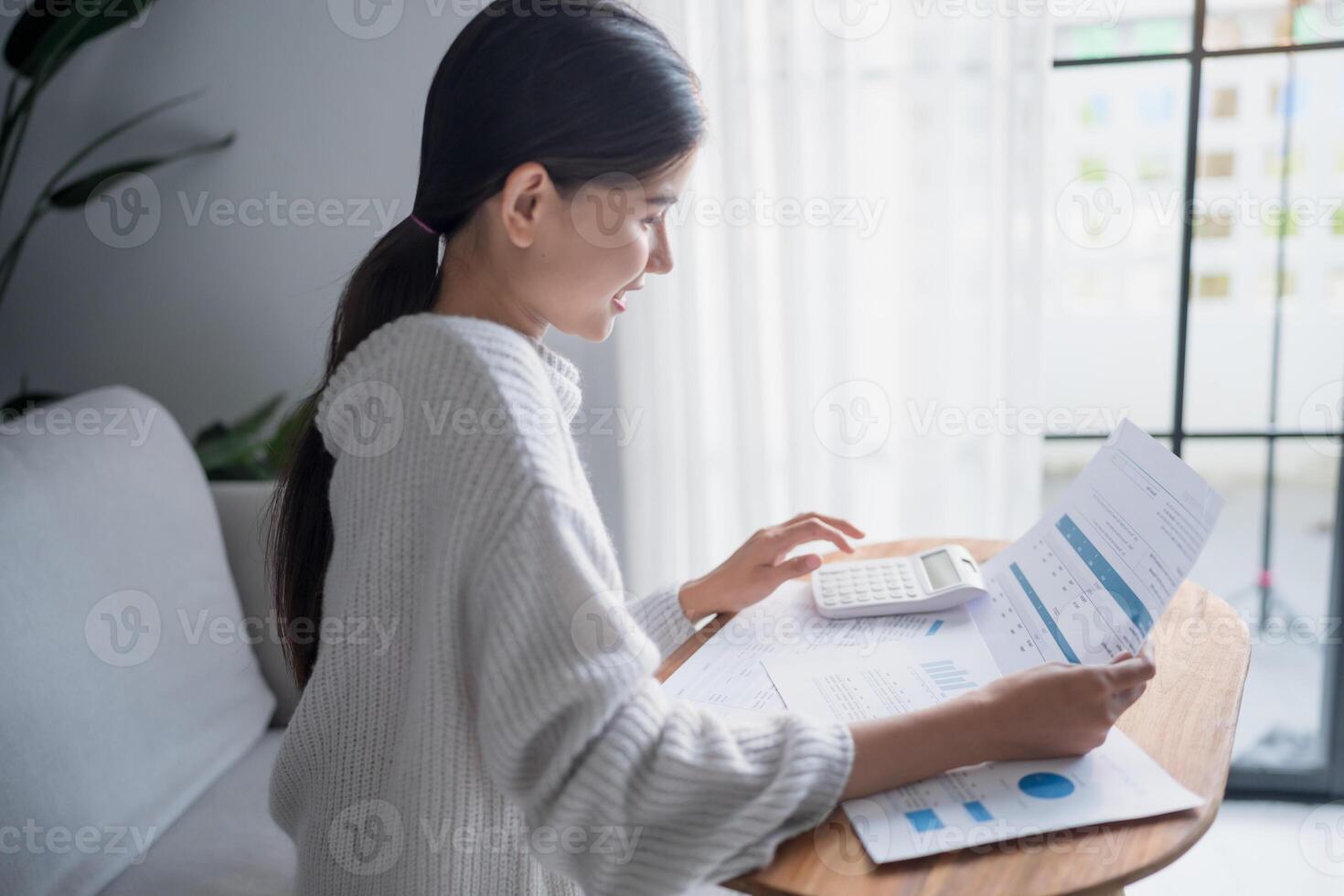 Businesswoman Accountant analyzing investment charts Invoice and pressing calculator buttons over documents. photo