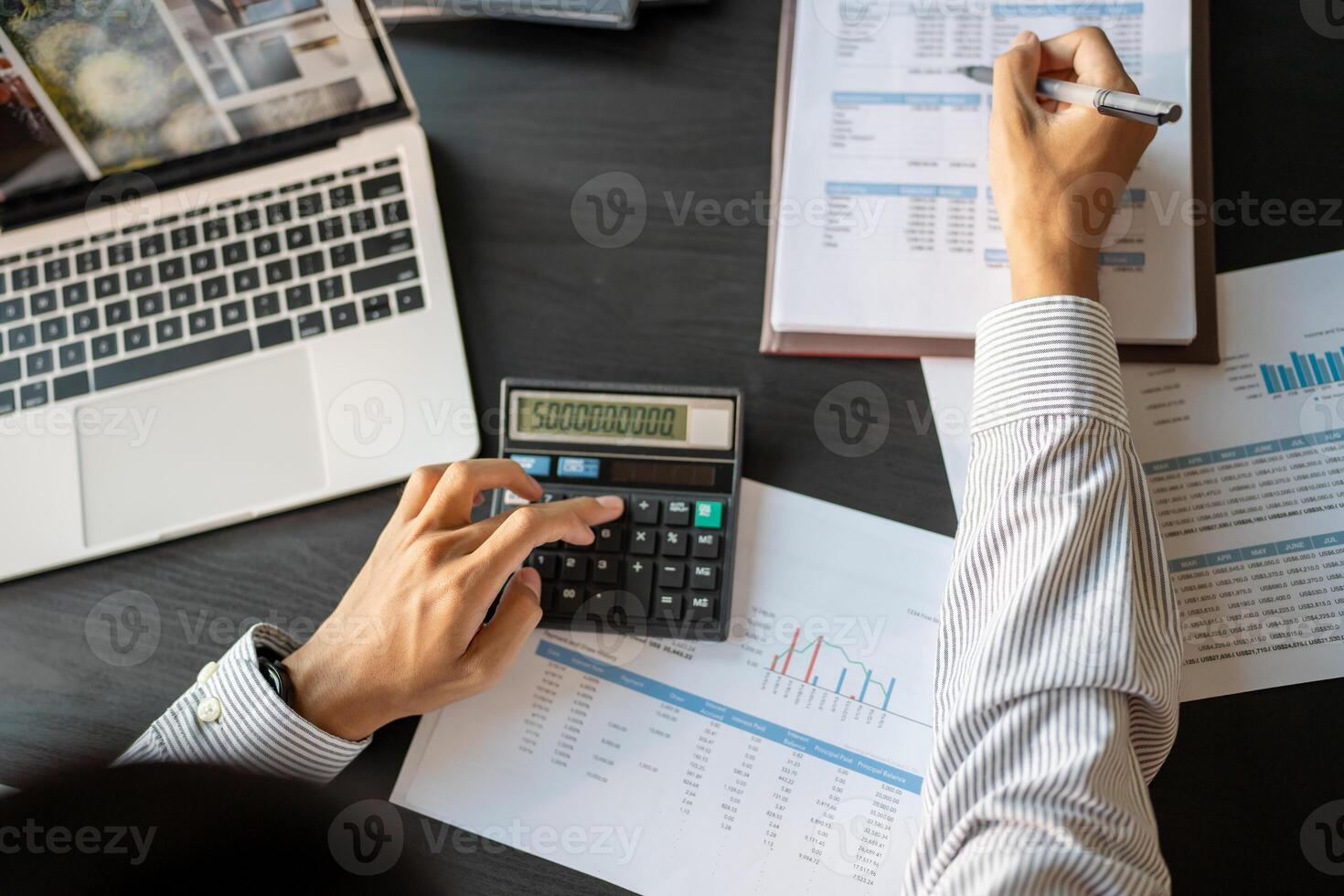 businessman using calculator and laptop to calculate financial reports photo