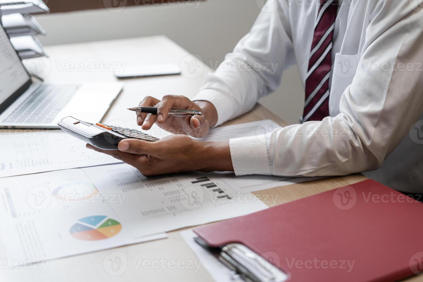 a man in a white shirt and tie is using a calculator photo