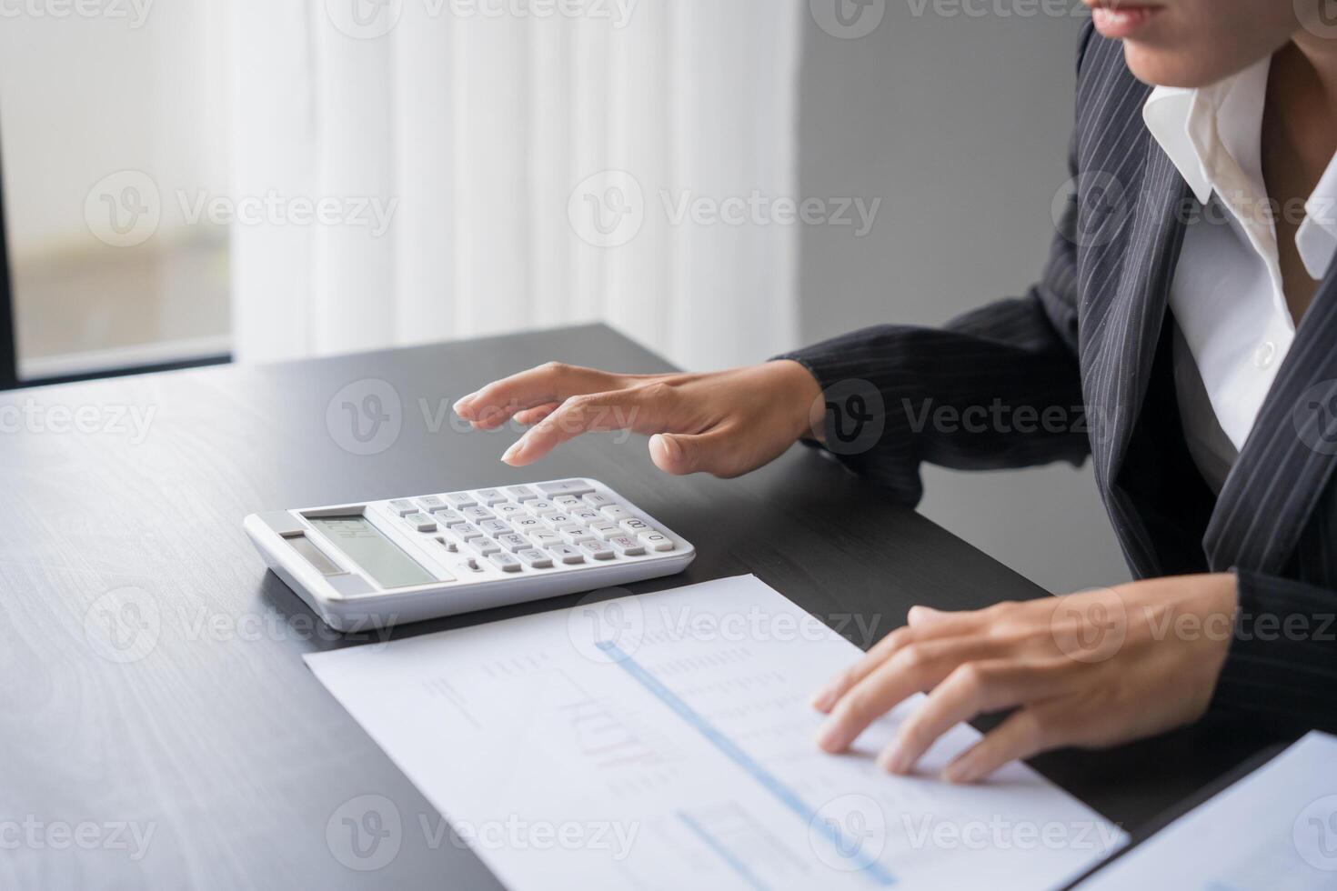 a middle ages woman in a business suit is using a calculator photo