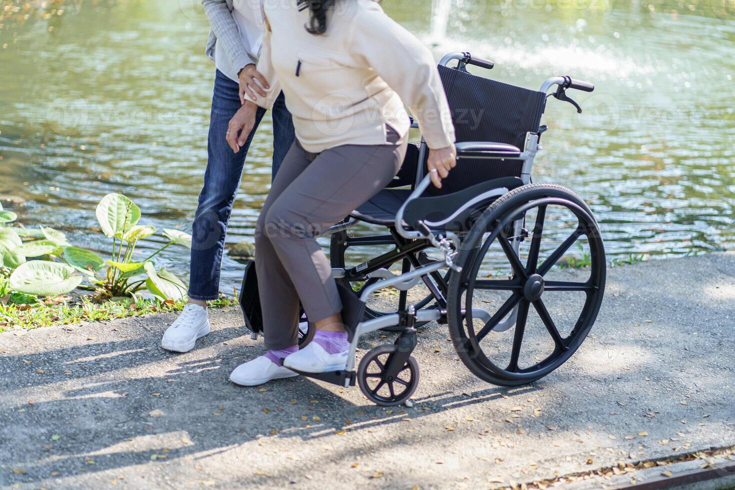 Nursing Young caregiver helping senior woman in wheelchair. photo