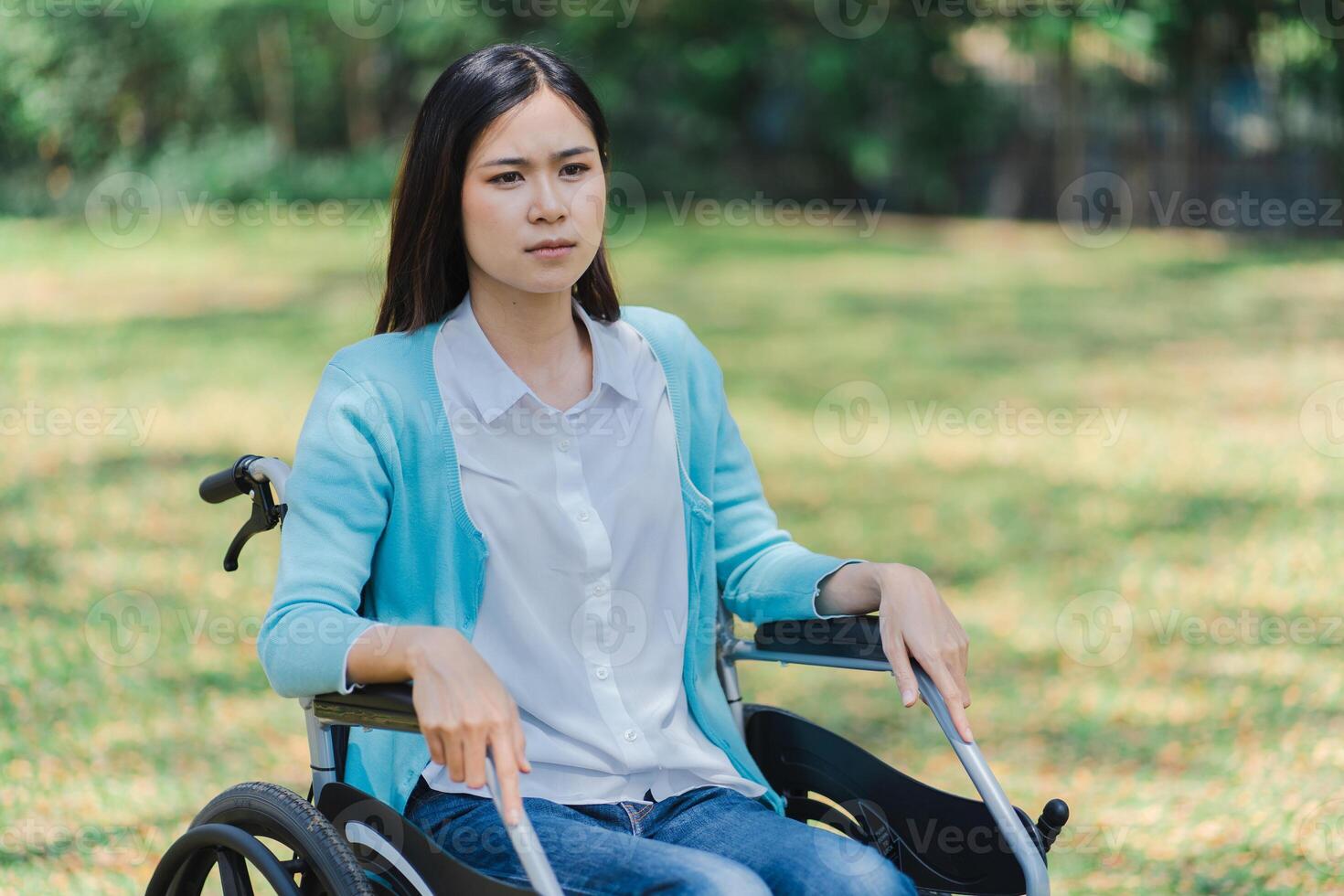 a sad woman in a wheelchair sitting on the grass photo
