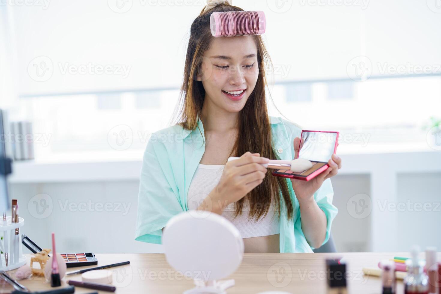 a woman is smiling while holding a makeup mirror photo