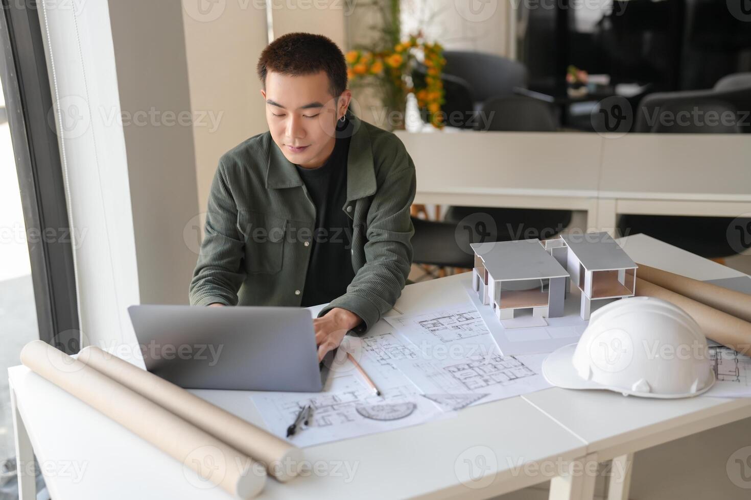 a engineer man sitting at a table with a laptop and construction plans photo