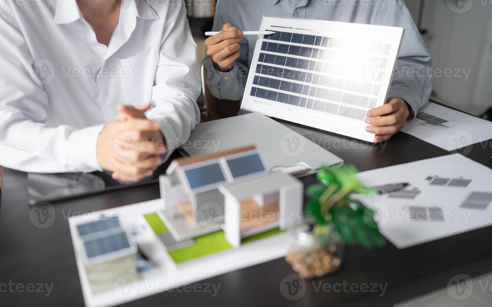 two engineers are holding a solar panel and a model of a house photo