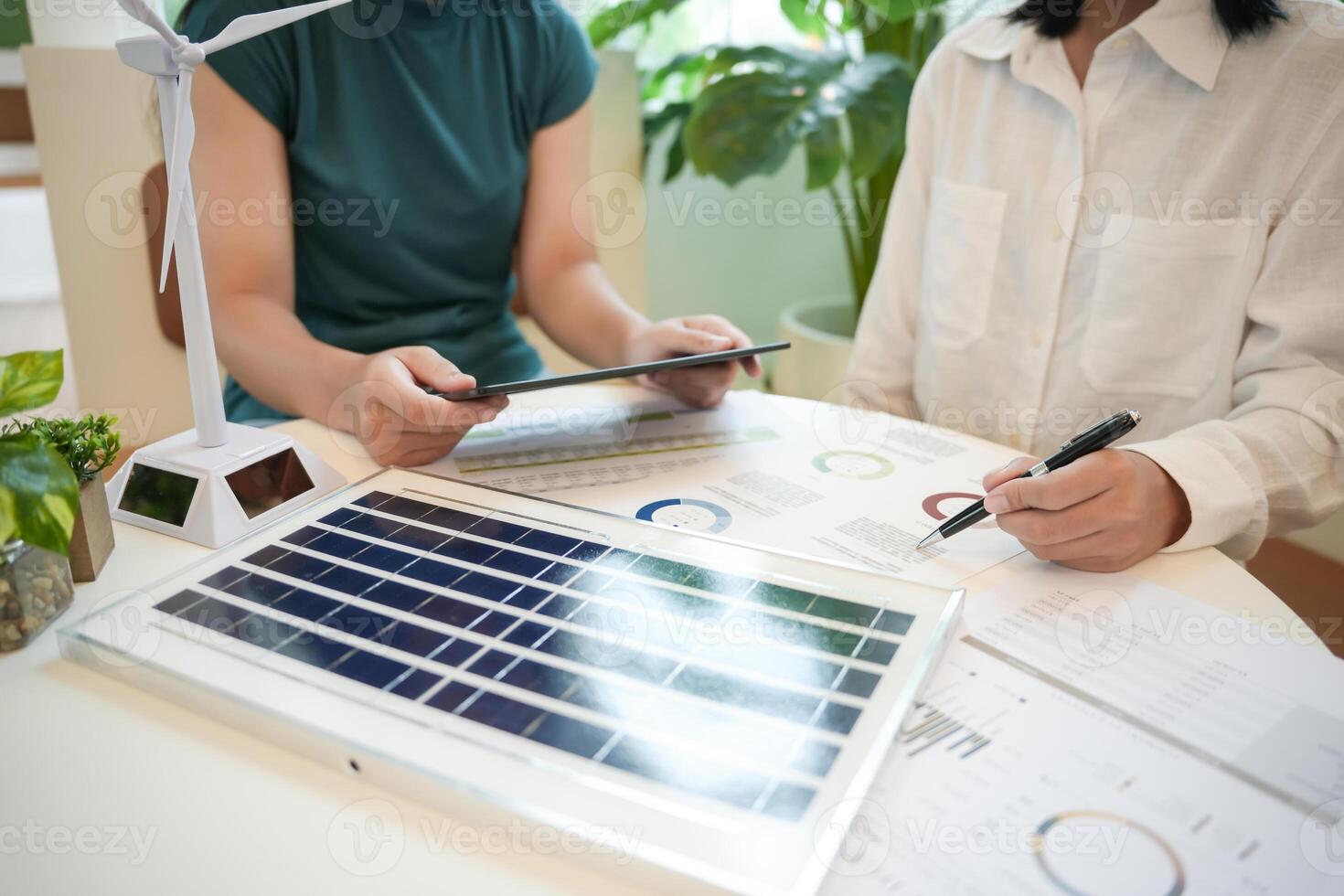 two people sitting at a table with a laptop and a wind turbine photo