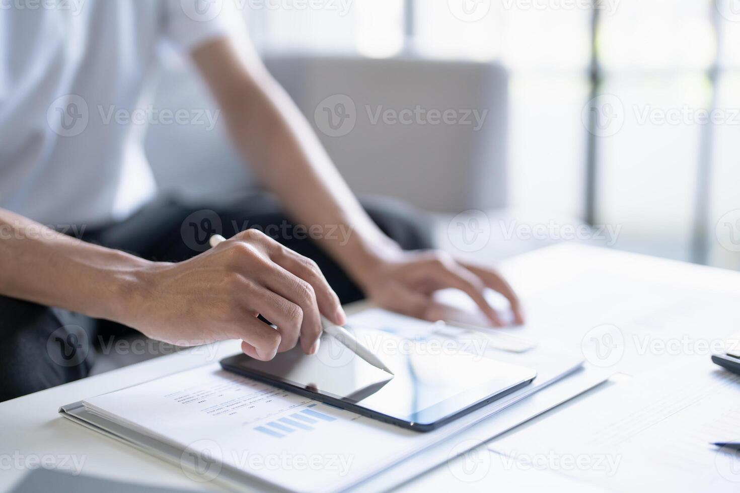 a businessman is using a tablet and pen on a desk photo