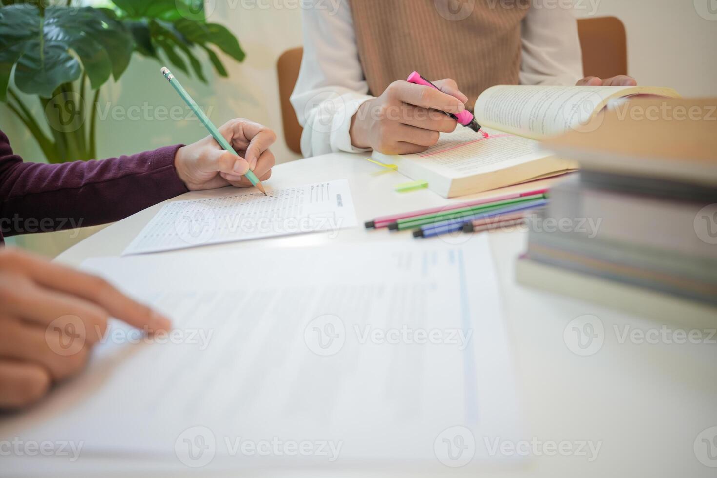 Learning with friends two people sitting at a table with books and pens photo
