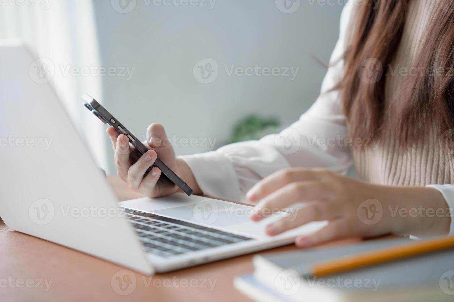 a student woman is using her smartphone while sitting at a desk photo