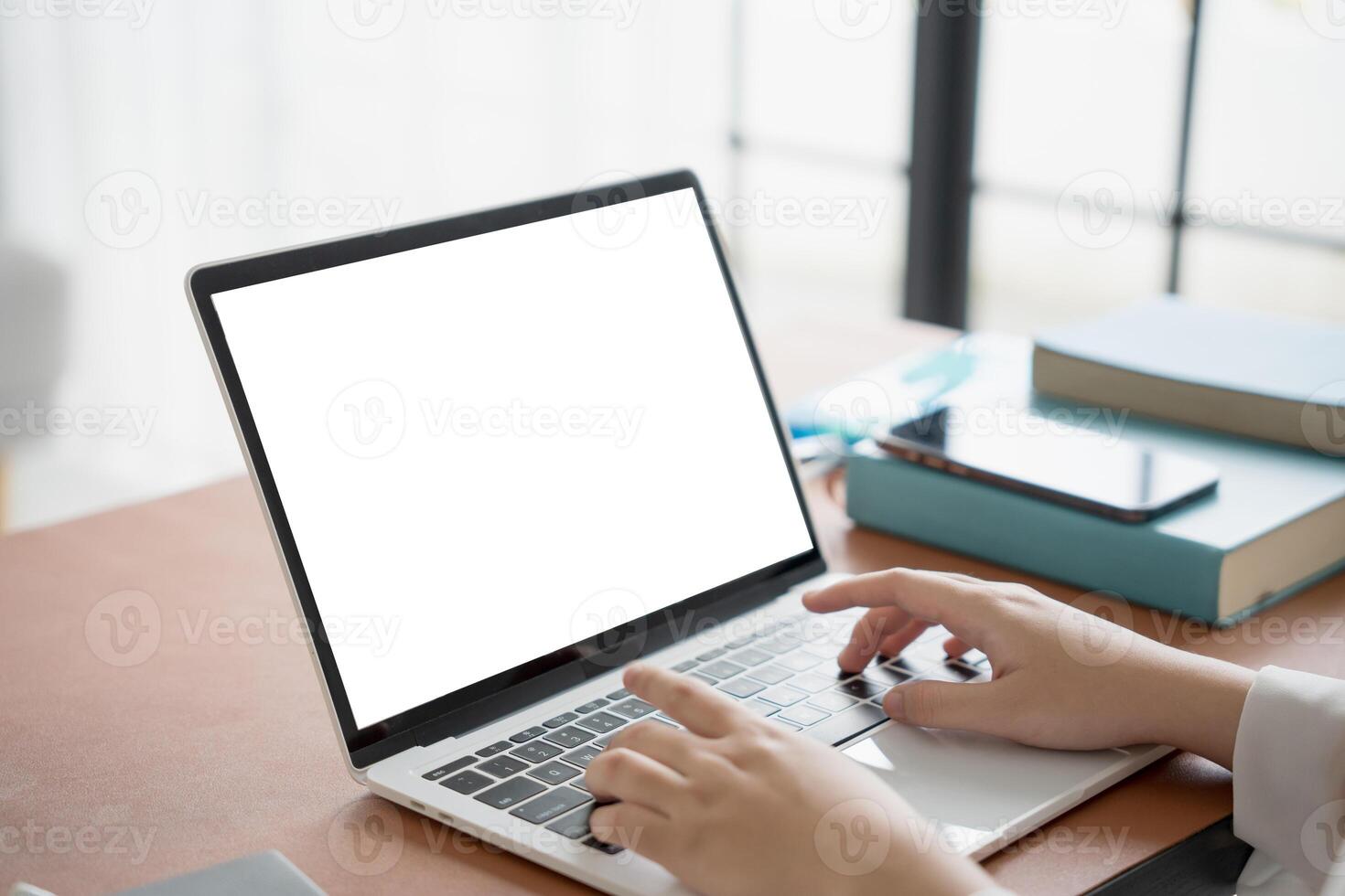 a person typing on a laptop computer with a blank screen photo