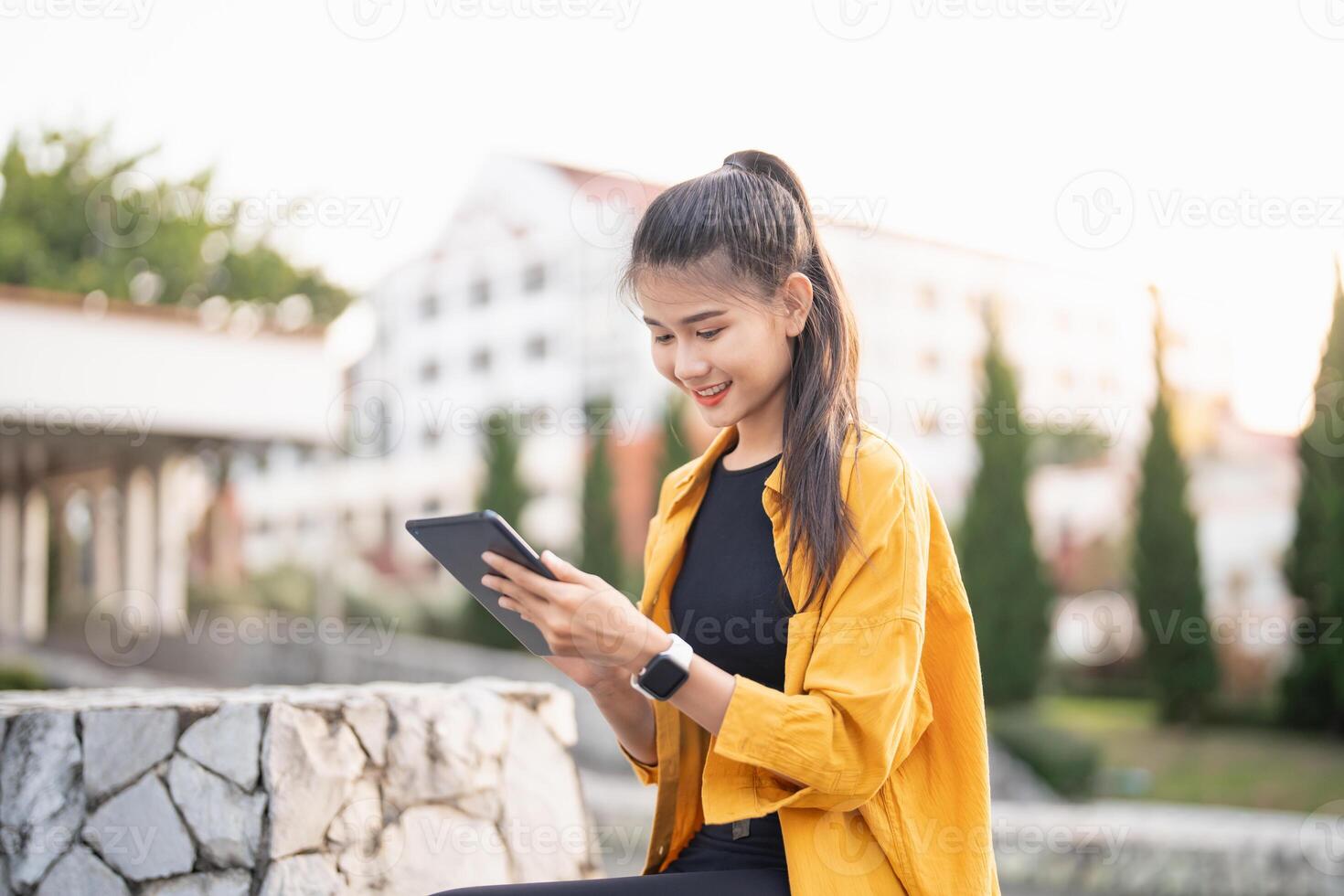 asian woman using tablet computer in outdoor setting photo