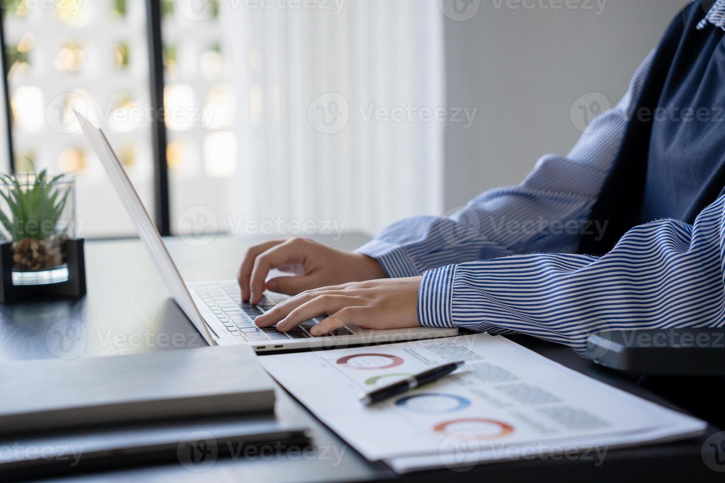 a person sitting at a desk using a laptop computer photo