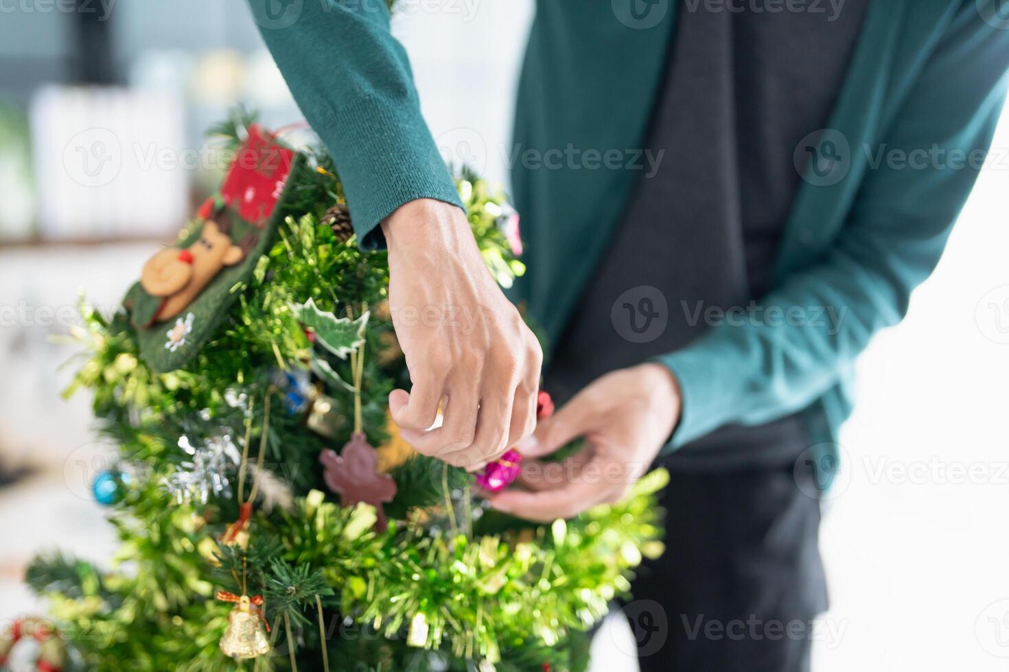 a man is decorating a christmas tree with ornaments. photo
