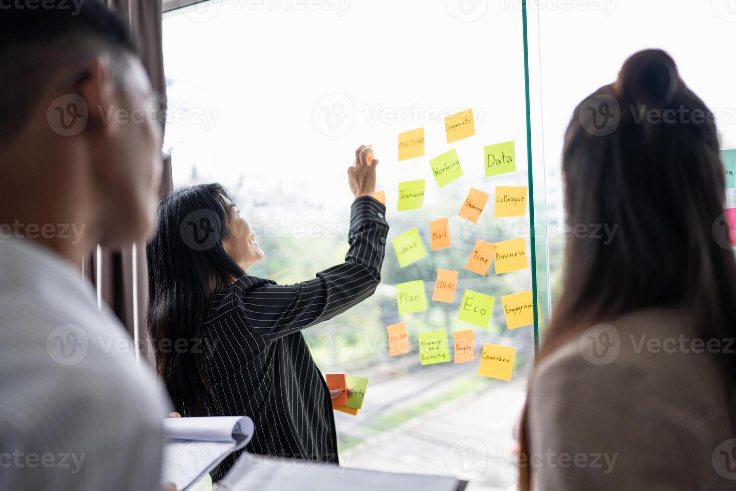 a group of people standing around a window with sticky notes on it photo