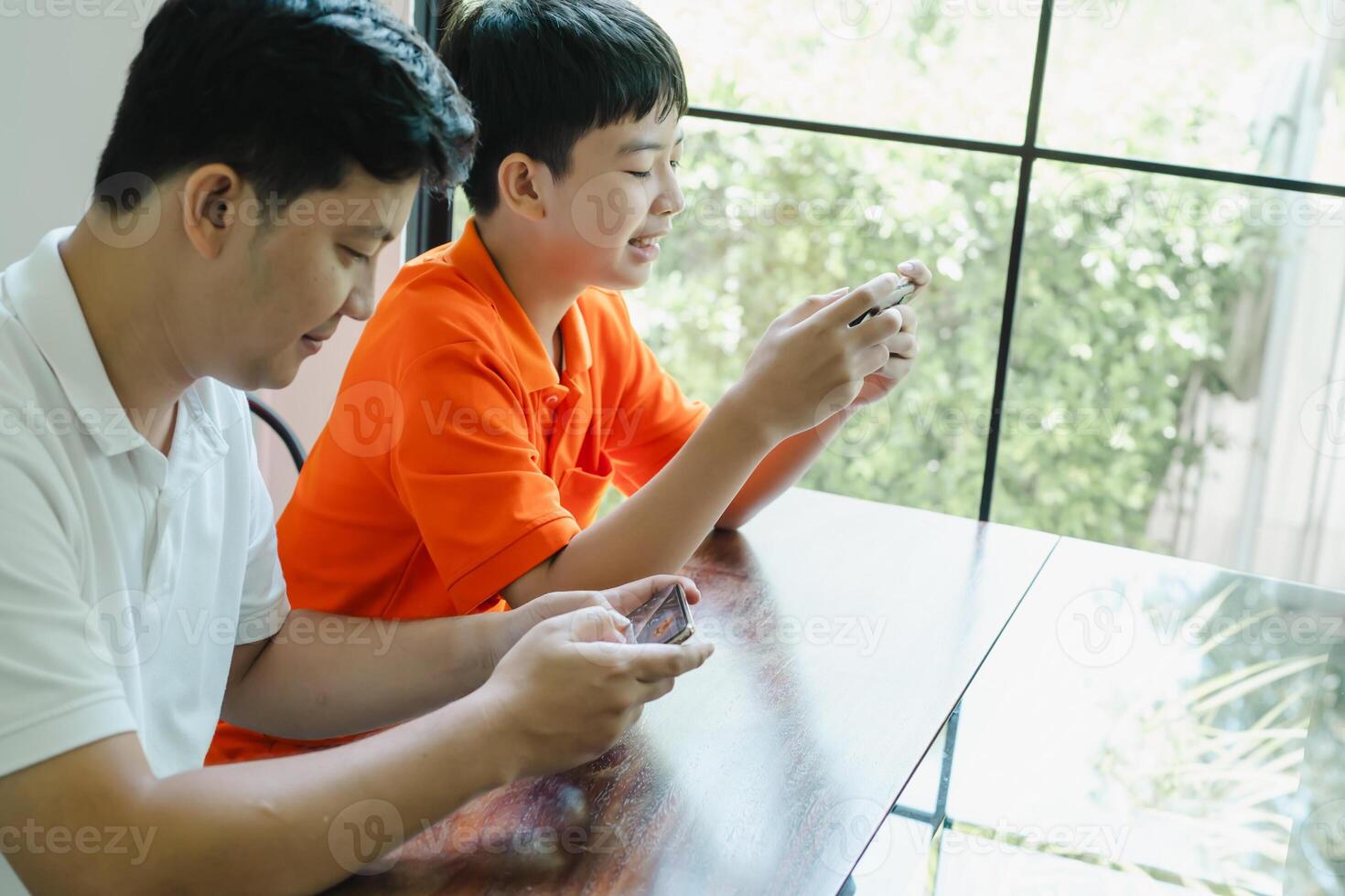 father and son with mobile phone playing games together dad spend time with children family photo
