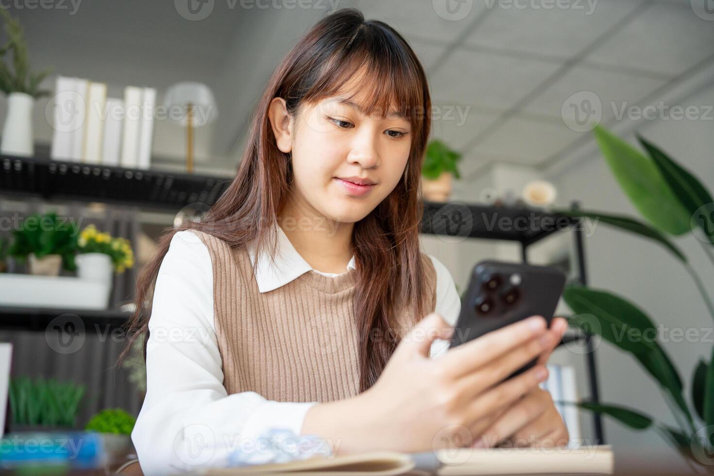 Student asian woman using smart phone in dorm room college mobile addict spending time checking news technology ecommerce photo